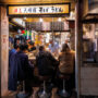 View from the street into a small restaurant in Shinjuku, Tokyo, where diners are eating at the counter with the chef in front of them