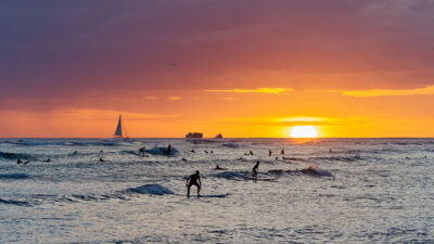 View from Waikiki beach at beautiful sunset with silhouettes of swimmers and surfers