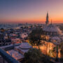Aerial night cityscape with small residential buildings, illuminated mosque with a minaret and distant lights of ships in the sea, İstanbul, Turkey